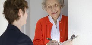 An elderly lady answering the door to a potential scammer trying to obtain personal information