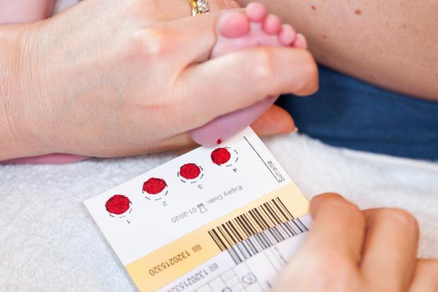baby's foot being held during newborn blood sport screening