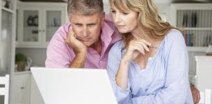 A man and a woman reading a laptop screen together.