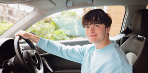 Image shows a young driver sitting behind the wheel of a car