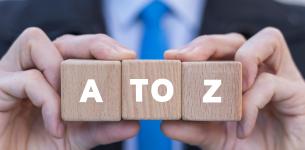 Building blocks showing A to Z that are being held up close to the camera by man in a suit