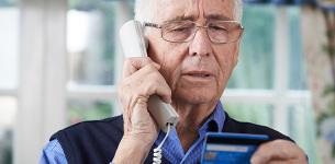 An elderly gentleman giving credit card details over the phone to a scammer.